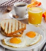 Breakfast with two fried eggs, toasts, juice and coffee.